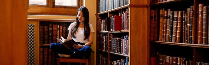 Student reading book in old library.