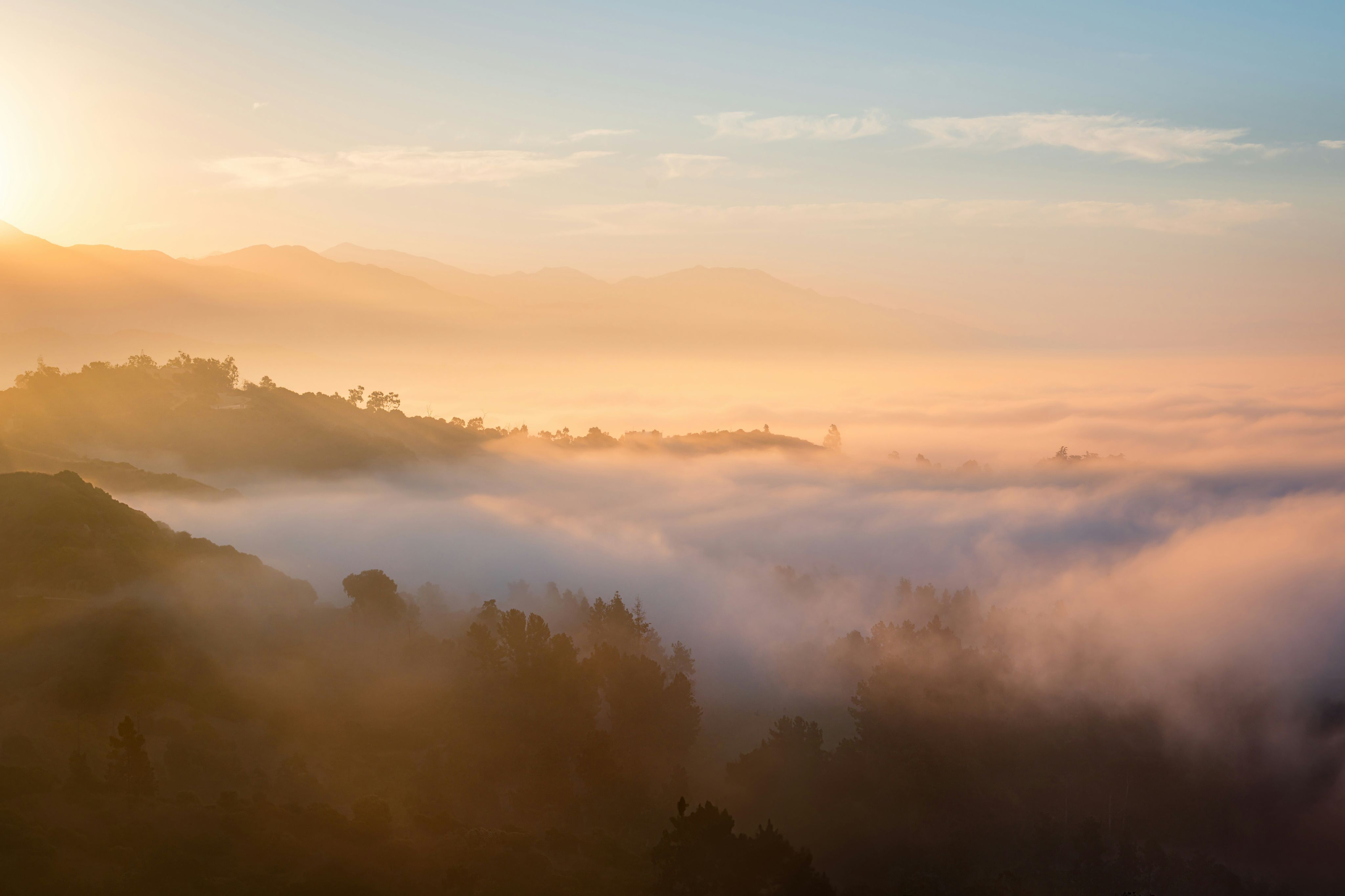 Golden sunrise illuminates a foggy mountain landscape.