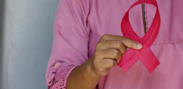 Woman holds pink breast cancer awareness ribbon. 