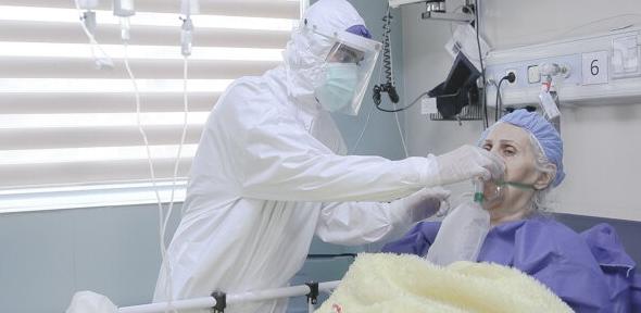 A clinician helping a COVID-19 patient with an oxygen mask in a hospital in Iran