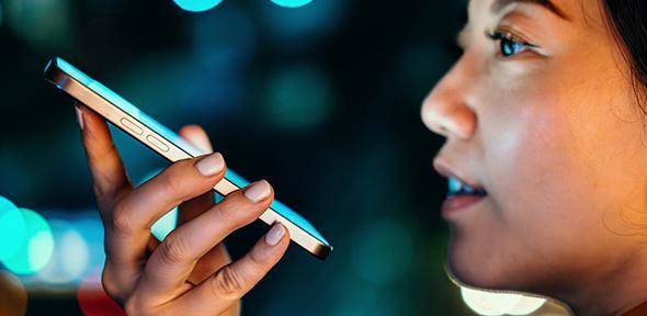Young woman talking with AI voice virtual assistant on smartphone