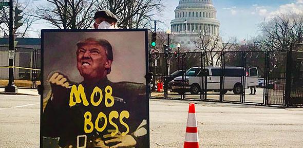A protester holds a sign comparing President Trump to Italian dictator Benito Mussolini.