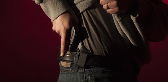 A man drawing a conceal carry pistol from an inside the waistband holster