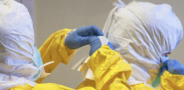 Healthcare workers checking each other’s personal protective equipment 