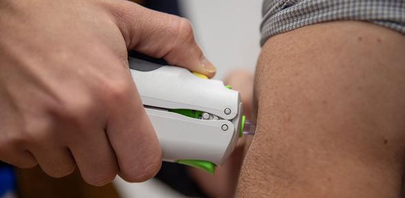Vaccine being administered by needle-free injection into a volunteer's arm