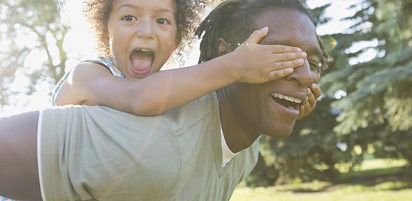 Portrait of playful girl covering father's eyes in park