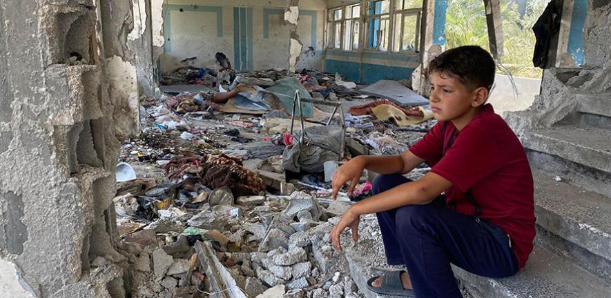 Boy sitting in the rubble of a destroyed UNRWA school in Nuseirat, Middle Areas, Gaza 2024