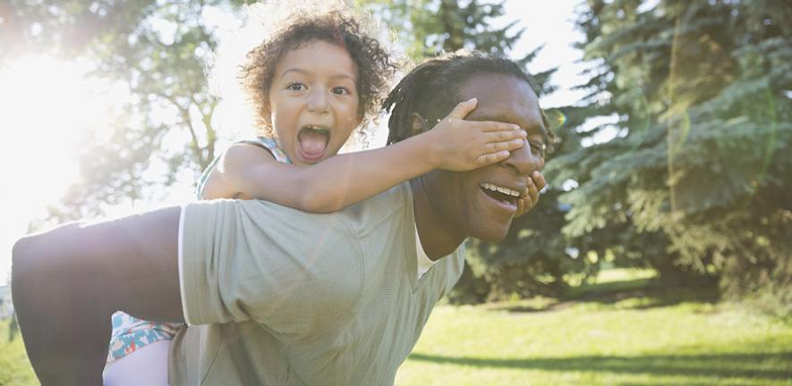 Portrait of playful girl covering father's eyes in park