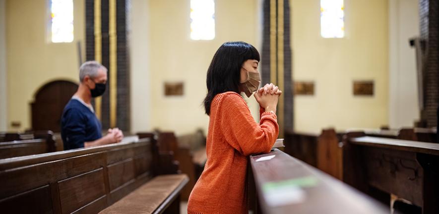 People in church praying with covid-19 restrictions 