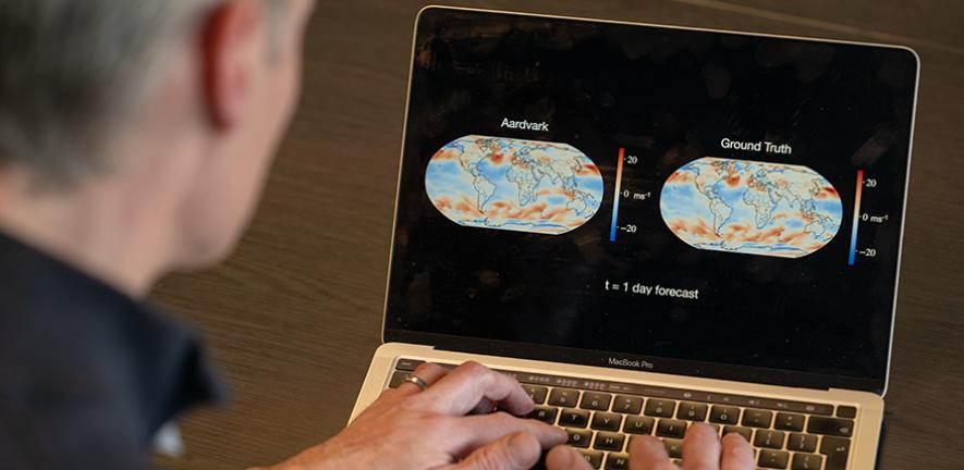 Scientist looking at a computer screen with two weather forecasts