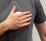 Person wearing a grey t-shirt holding a palm-sized device to their chest