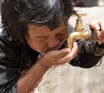 A young child drinks from a water tap