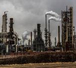 Factories with smoke under cloudy sky
