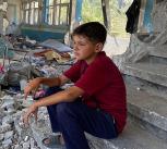 Boy sitting in the rubble of a destroyed UNRWA school in Nuseirat, Middle Areas, Gaza 2024