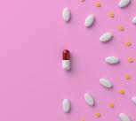 Pills and a capsule on pastel pink colored background. 3D rendered image.