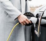 View of woman's hand plugging in charging lead to her electric car