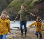 A father and two sons running on a beach