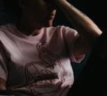 Woman sitting on sofa in the dark, placing a hand to her forehead.