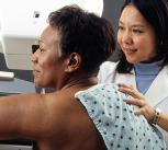 Female doctor standing near woman patient doing breast cancer scan
