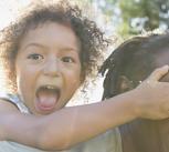 Portrait of playful girl covering father's eyes in park
