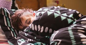 Teenager asleep and wrapped in a blanket