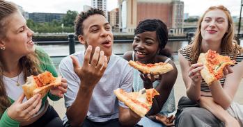Teenagers eating pizza by the river