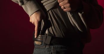 A man drawing a conceal carry pistol from an inside the waistband holster