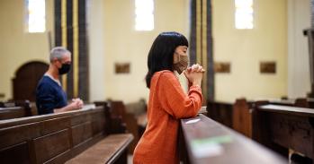 People in church praying with covid-19 restrictions 