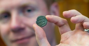 Prof. Rory Naismith holding a silver Byzantine coin in the Fitzwilliam Museum, Cambridge. Photo: Adam Page