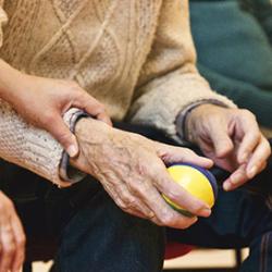 Woman touching the arm of an elderly man holding a juggling ball