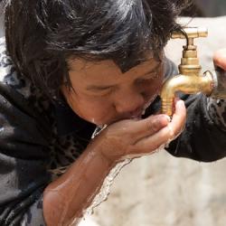 A young child drinks from a water tap