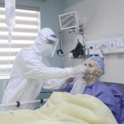 A clinician helping a COVID-19 patient with an oxygen mask in a hospital in Iran