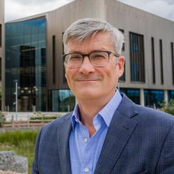 Professor Martin Bennett standing outside the Victor Phillip Dahdaleh Heart and Lung Research Institute