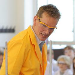 Dr Pete Wothers giving a chemistry demonstration to an audience at the Cambridge Science Festival including David Willetts, Minister for Universities and Science.