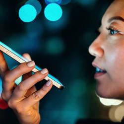 Young woman talking with AI voice virtual assistant on smartphone