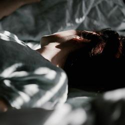 A person laying in a bed under a blanket
