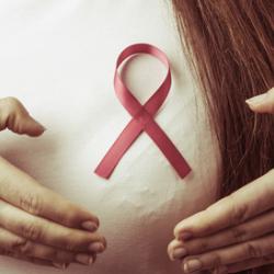 Breast cancer. Female hands make heart on pink ribbon
