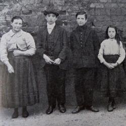 Black and white photograph of a family lined up against a wall, taken from a report on the physical welfare of mothers and children.