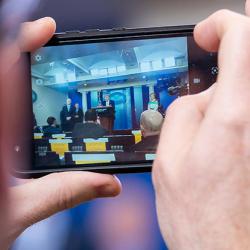 A reporter takes a photo of Donald Trump during a White House coronavirus briefing in April