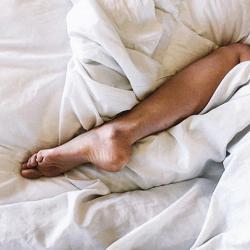 Leg sticking out from a white blanket