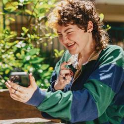Two autistic friends sitting outside using stim toys and laughing at their phones