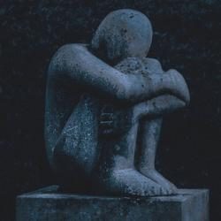 Statue of a figure hugging its knees
