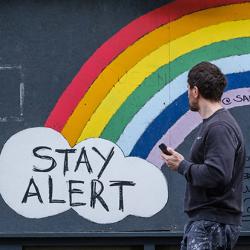 Man walking past Stay Alert/Save Lives artwork