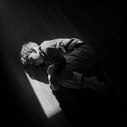 Black and white image of boy curled up on the floor