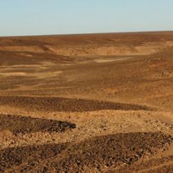 Left: A view across a valley in the Messak landscape. Right: A Levallois core, a distinctive type of Middle Stone Age stone tool, recovered on the surface of the Messak