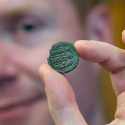 Prof. Rory Naismith holding a silver Byzantine coin in the Fitzwilliam Museum, Cambridge. Photo: Adam Page