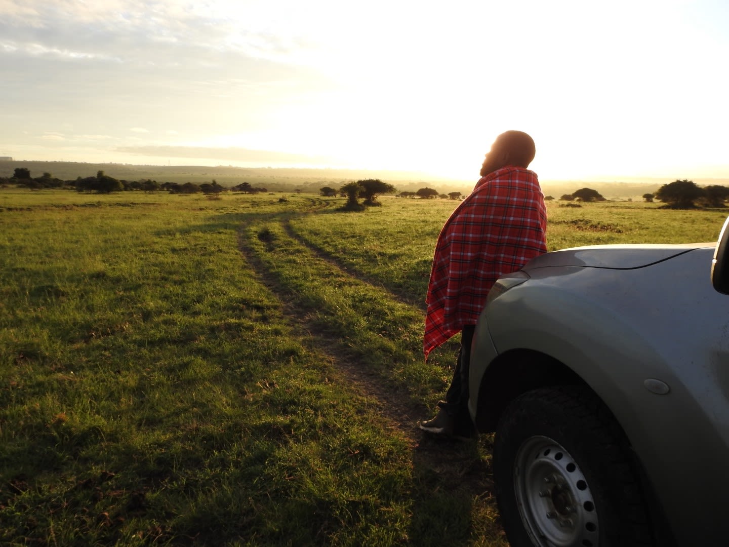 Nyandire Reinhard leaning on car looking out at sunset