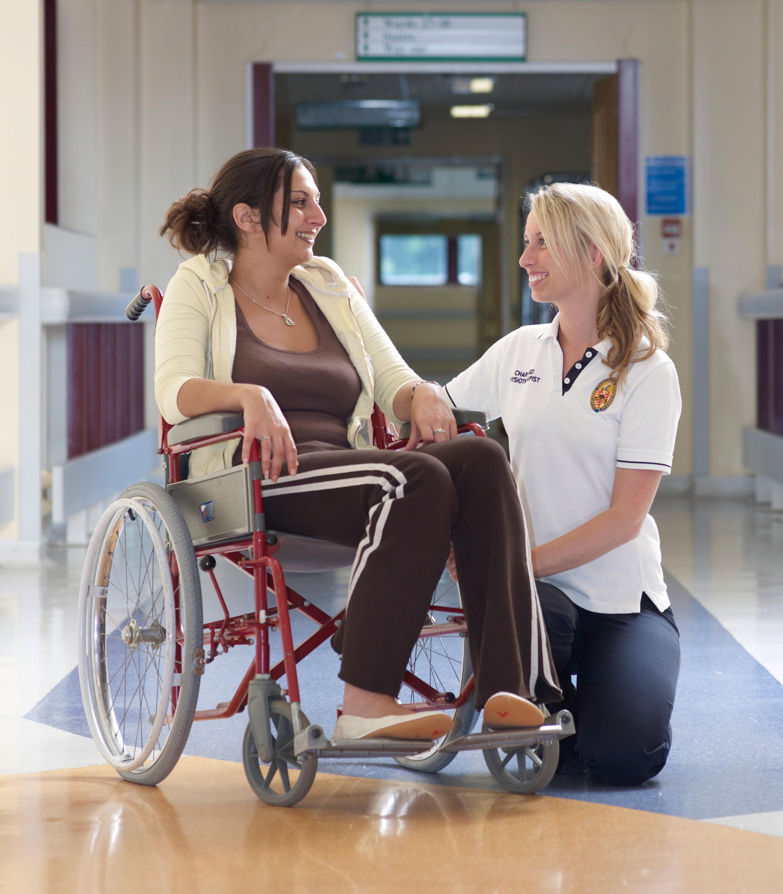 Physiotherapist with patient in hospital corridor, UK. 