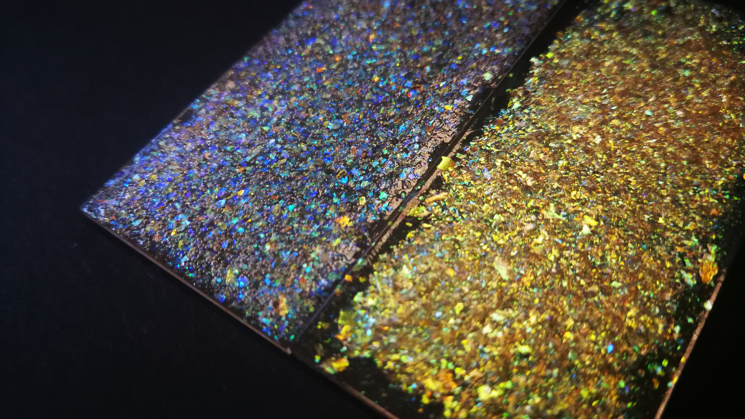 Close up of blue and gold glitter on a black background