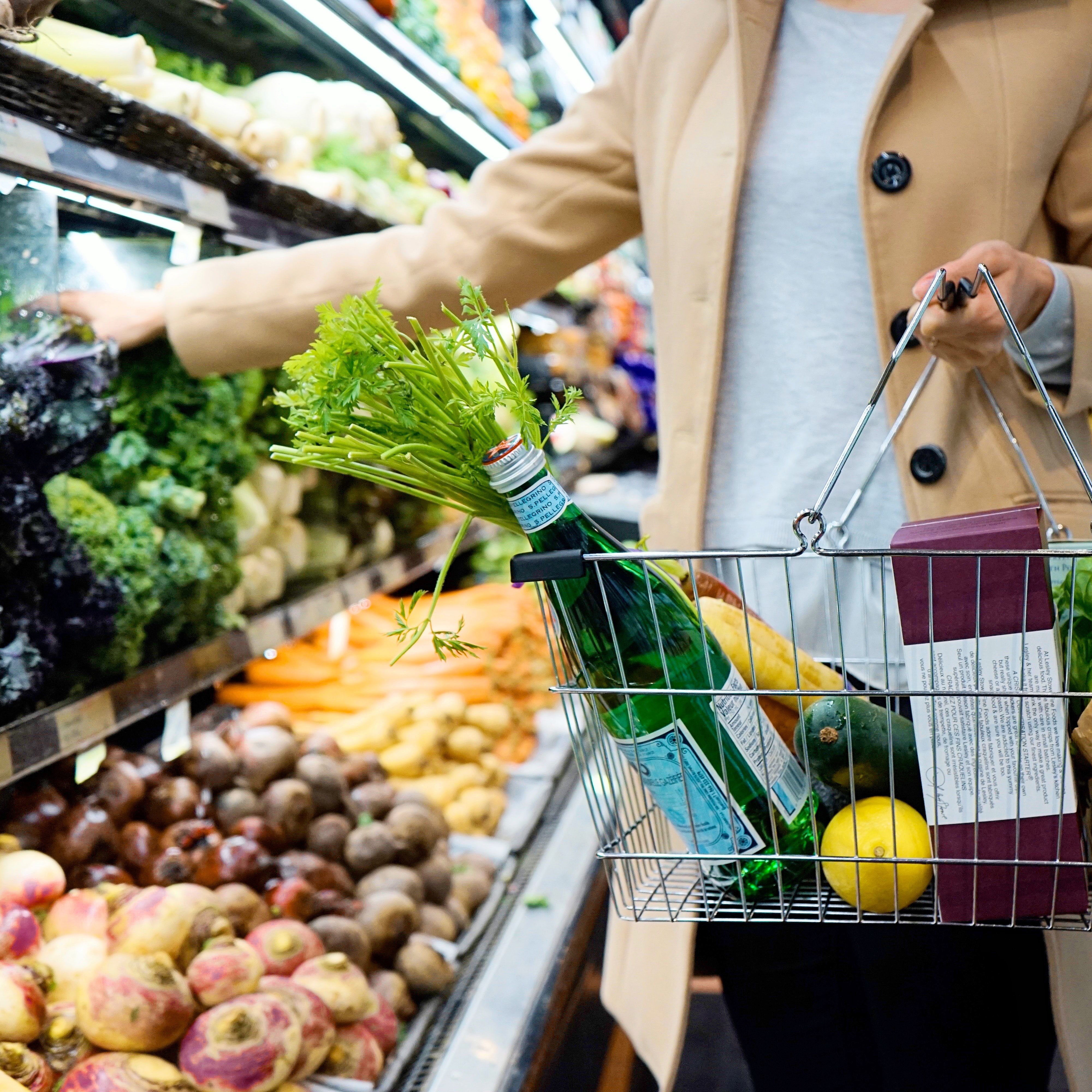 Woman shopping with basket in supermarket